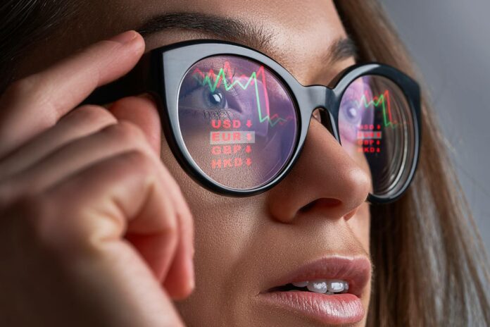 Kursy walut i wykresy odbijające się w okularach kobiety